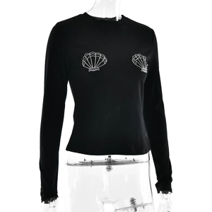 Detail of black slim-fit long sleeve top with rhinestone shell patterns on chest