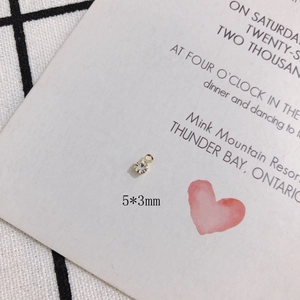 Macro detail of 5x3mm gold plated rhinestone charm on decorative invitation card