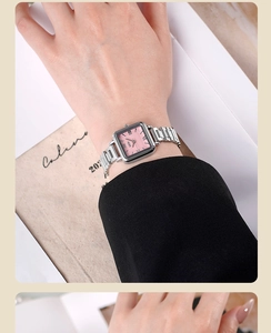 Détail d'une montre à cadran carré rose et bracelet en acier argenté sur fond de magazine
