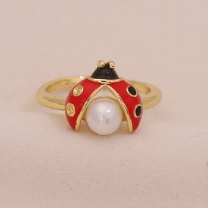 Macro shot of a ladybug ring with red wings and a white pearl on a gold band