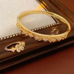 Close-up of gold-plated flower bracelet and ring set with sparkling zircon inlays