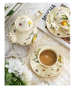 Detail view of floral and lemon ceramic tea set with gold trim on white lace tablecloth