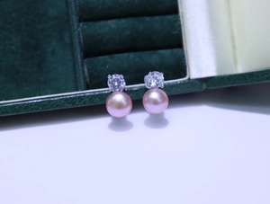 Detail view of pink freshwater pearl earrings with clear stones on green velvet
