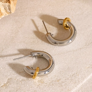 Two-tone silver and 18k gold plated stainless steel C-shaped earrings on stone background