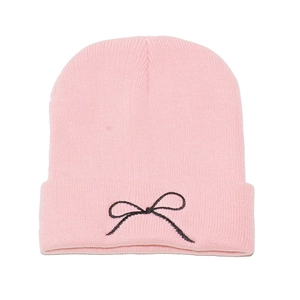 Close-up of pink ribbed beanie showing black embroidered bow detail and fine knit texture