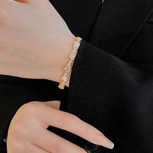 Macro detail of luxury gold bracelet with pink square stones and floral white crystals