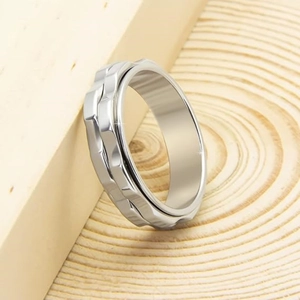 Macro shot of silver rotating gear ring for stress relief on natural wooden surface