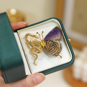 Exotic golden snake and butterfly brooch with purple wings held in a green velvet jewelry box