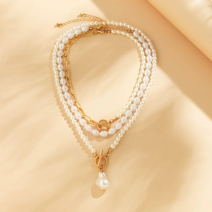 Detail of layered gold chain necklace set with baroque pearl and mixed white beads