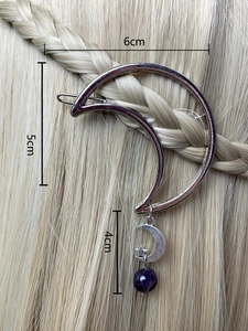Detailed view of a silver moon hair clip with purple crystal beads on golden hair