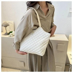 Détail d'un sac cabas matelassé blanc avec logo trèfle doré et bandoulière élégante