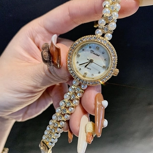 Elegant gold-tone women's watch featuring a pearl and rhinestone bracelet with shell dial
