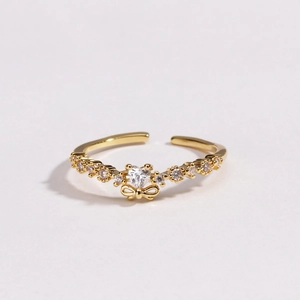 Détail d'une bague nœud dorée avec cristal en cœur et anneau réglable femme