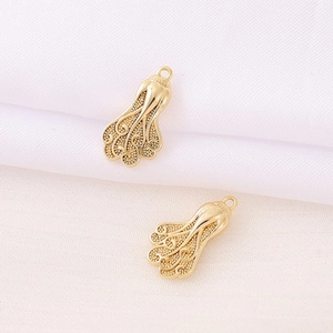 Close-up of golden fan-shaped metal pendants with hollow patterns for DIY jewelry