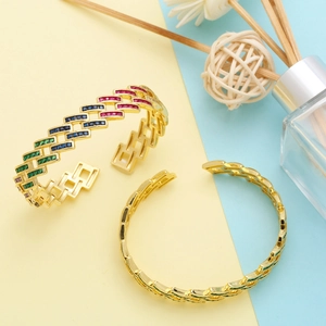 Macro shot of gold plated open bangle with vibrant multi-color zircon stones and chain texture