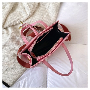 Interior view of pink leather tote bag showing red striped strap and zipper compartment