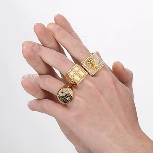 Three gold hip hop rings featuring lion head, cross and tai chi patterns on models hand