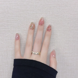 Pink gradient press-on nails with gold floral art and a wavy diamond-set ring