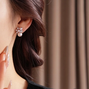 Elegant silver cluster earrings with pearls and cubic zirconia on a model's ear
