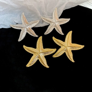 Dettaglio di orecchini a stella marina in oro e argento con superficie strutturata