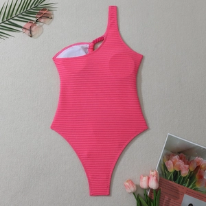 Gros plan du maillot de bain rose côtelé à une épaule avec bretelle tressée et accessoires