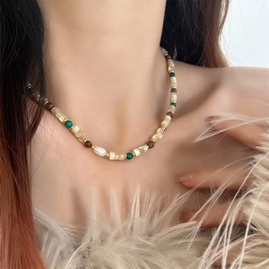 Elegant beaded necklace with freshwater pearls and green stones on a female model