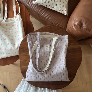 Close-up of floral print cotton canvas tote bags with vintage labels on wooden table