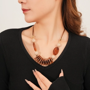 Detail of beads and round pendants on retro leather cord necklace worn by model