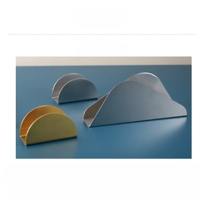 Modern brushed stainless steel napkin holders in silver and gold on a dark blue surface