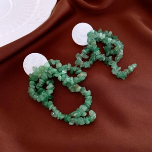 Macro shot of irregular green stone stud earrings on vintage dark silk fabric background