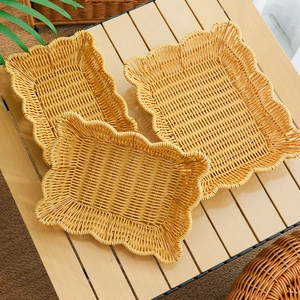 Three-piece set of wave-edged faux rattan fruit baskets in natural brown on a wooden table