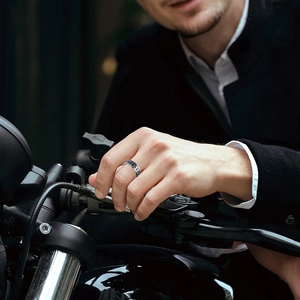 Men's silver and black skull ring in biker style worn on motorcycle handlebar