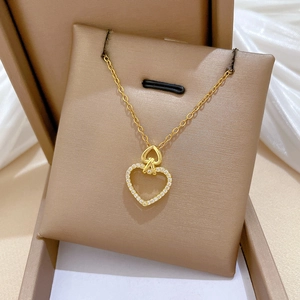 Detail view of a gold double heart pendant necklace with small crystals in a beige gift box