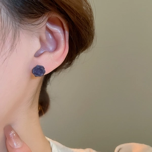 Gros plan d'un mannequin portant une puce d'oreille rose en résine noire mate de style vintage