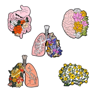 Cinq broches créatives en métal représentant des organes anatomiques et fleurs sur fond blanc
