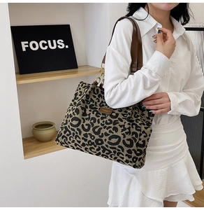 Detail of leopard print tote bag featuring brown leather straps and spacious design