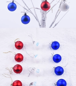 Close-up of patriotic Christmas ball ornaments with USA BRAVE LIBERTY text on tree branch