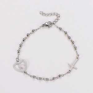 Detailed close-up of silver bead bracelet with heart pendant and religious cross charm