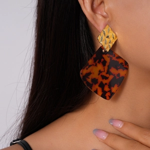 Detail of amber tortoiseshell geometric diamond earrings worn by model for elegant style