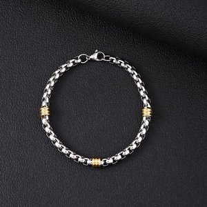 Detail of silver box chain with gold textured cylinders and lobster clasp on black leather