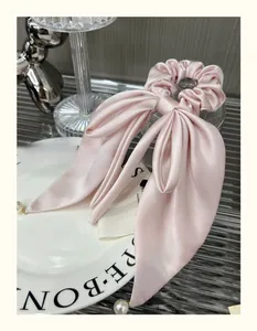 Detail of pink satin ribbon hair tie with bow and long streamers on a ceramic plate