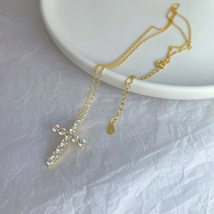 Close-up of S925 sterling silver gold cross necklace with extension chain on white tray