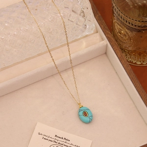 Detailed view of an oval turquoise stone pendant with red gemstone in a jewelry box