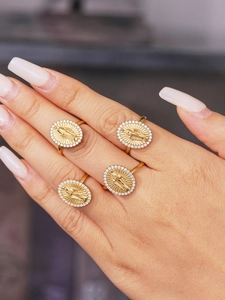 Close-up of gold stainless steel oval rings with 5A zircon and holy figure embossing
