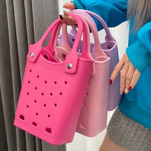 Detail of vibrant waterproof EVA beach bags in pink and purple with rivets and holes