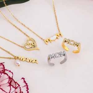 Detail shot of gold MOM and MAMA necklaces and rings with crystals and pink flowers