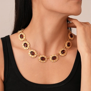 Detail of vintage gold necklace with red gemstones and enamel on female model's neck
