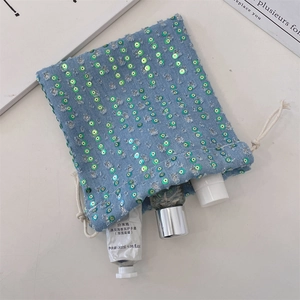 Detail of light blue denim drawstring pouch with green sequins and white cotton rope