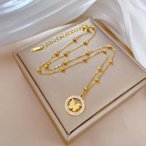 Close-up of a gold butterfly pendant with rhinestones on a beaded chain and silk base