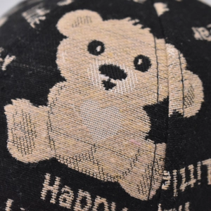 Macro shot of embroidered bear pattern and Happy text on black fabric baseball cap